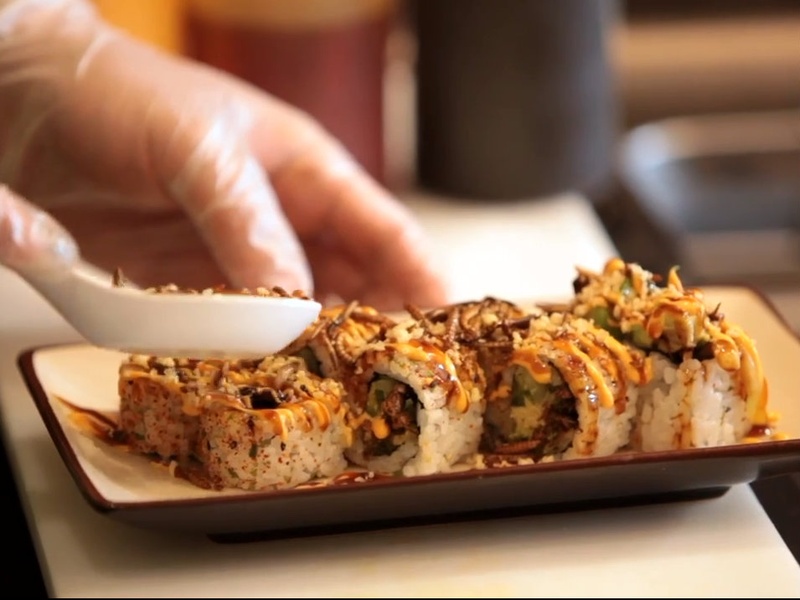 Chef Peter Yung sprinkles on mealworm tempura flakes on insect bug sushi roll